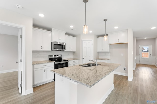 kitchen featuring stainless steel appliances, a kitchen island with sink, white cabinetry, and a sink