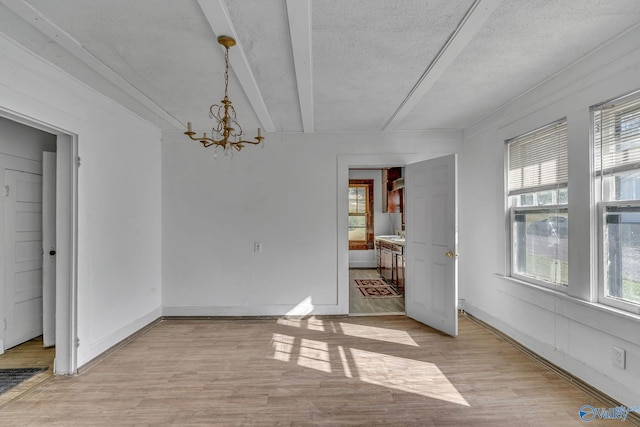 unfurnished dining area featuring plenty of natural light, a chandelier, light wood-type flooring, and a textured ceiling