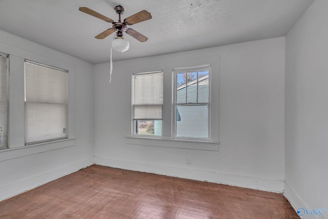 empty room with ceiling fan, wood-type flooring, and a textured ceiling