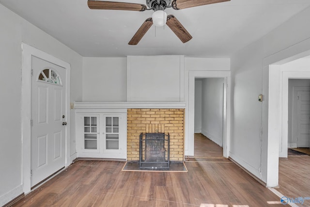 unfurnished living room featuring ceiling fan, hardwood / wood-style flooring, and a brick fireplace