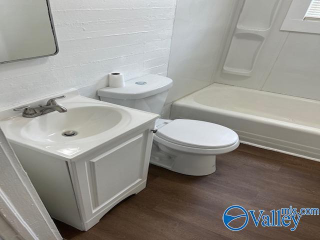 bathroom with wood finished floors, toilet, shower / washtub combination, and vanity