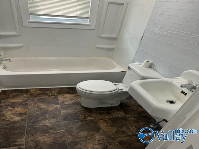 full bath featuring bathing tub / shower combination, toilet, and a sink