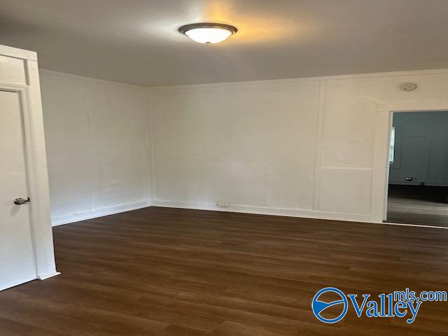 unfurnished room featuring wood finished floors and a decorative wall