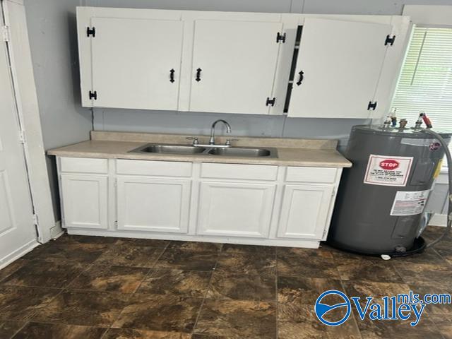 kitchen featuring white cabinetry, water heater, light countertops, and a sink