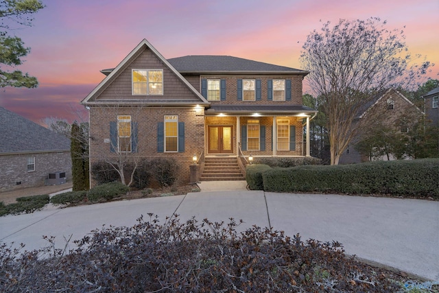 view of front of home featuring brick siding, stairway, and a porch