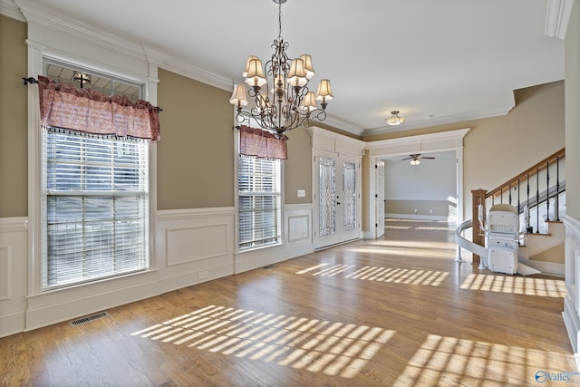 foyer featuring stairway, visible vents, wood finished floors, and ornamental molding