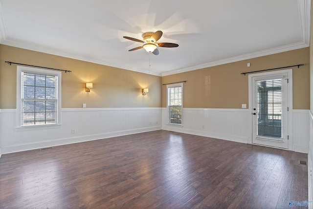 spare room with a wainscoted wall, wood finished floors, visible vents, a ceiling fan, and crown molding