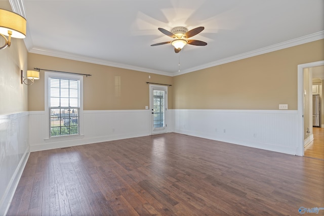 empty room featuring a wainscoted wall, crown molding, a ceiling fan, and wood finished floors