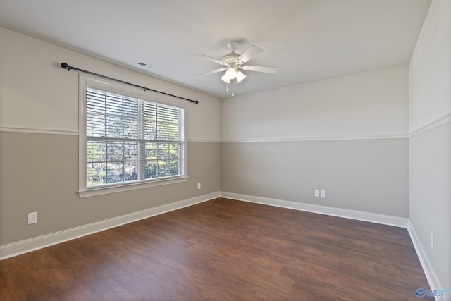 spare room featuring dark wood-type flooring, visible vents, ceiling fan, and baseboards