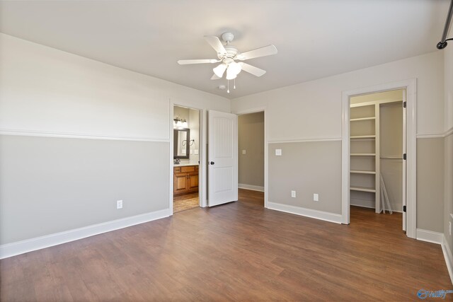 unfurnished bedroom featuring dark wood-style floors, a closet, a walk in closet, and baseboards