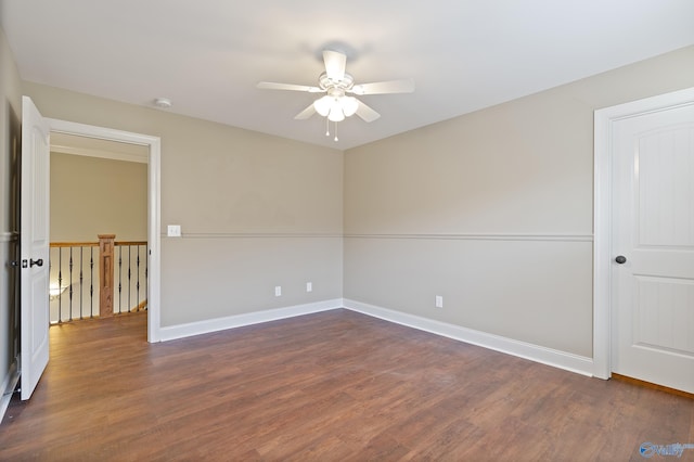 spare room featuring ceiling fan, baseboards, and dark wood finished floors