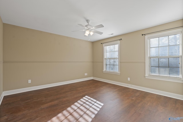 unfurnished room with ceiling fan, dark wood-type flooring, visible vents, and baseboards