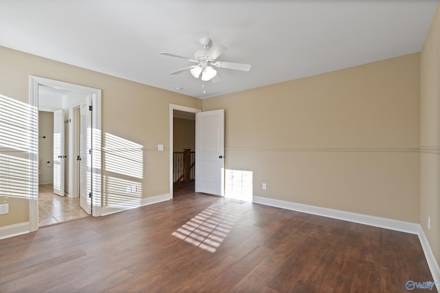 spare room with wood finished floors, a ceiling fan, and baseboards