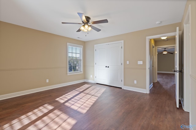 unfurnished bedroom featuring a closet, dark wood finished floors, baseboards, and ceiling fan