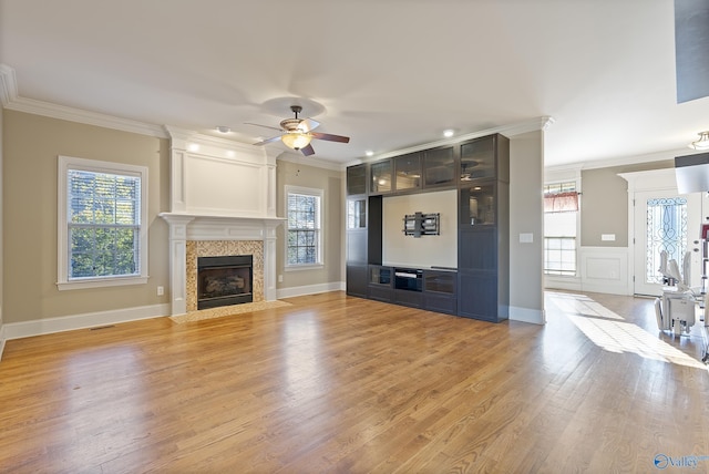 unfurnished living room with light wood finished floors, a tiled fireplace, and crown molding