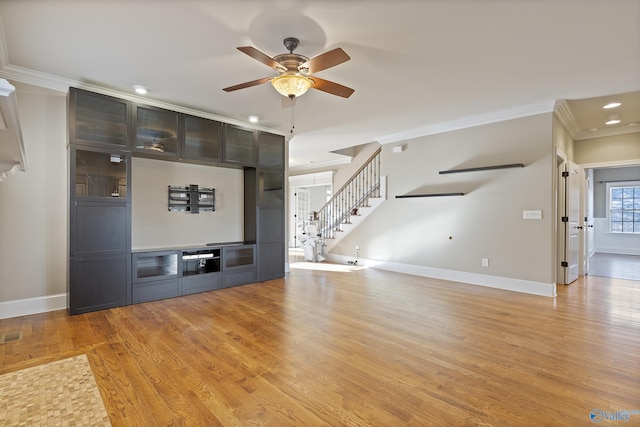 unfurnished living room with light wood finished floors, stairway, ornamental molding, ceiling fan, and baseboards