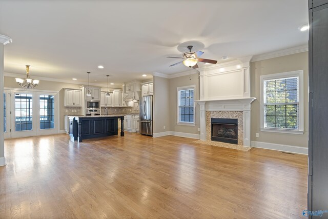 unfurnished living room with ornamental molding, a tile fireplace, and light wood-type flooring