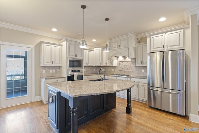 kitchen featuring decorative light fixtures, crown molding, stainless steel appliances, a sink, and light wood-type flooring