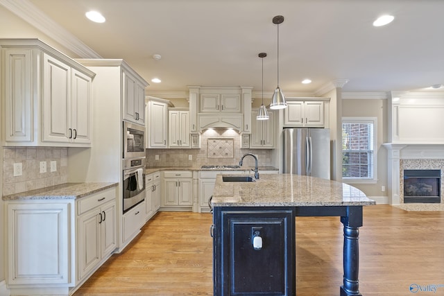 kitchen with stainless steel appliances, a sink, decorative light fixtures, and crown molding