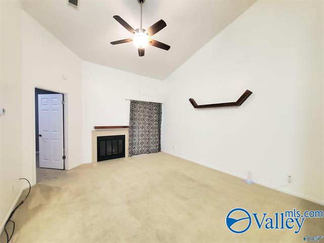 unfurnished living room featuring light carpet, a fireplace, ceiling fan, and high vaulted ceiling