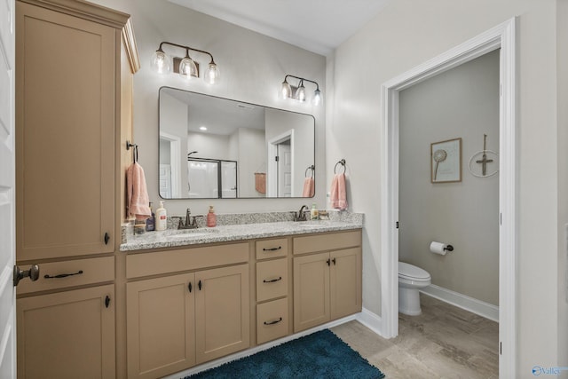 bathroom featuring a stall shower, toilet, double vanity, and a sink