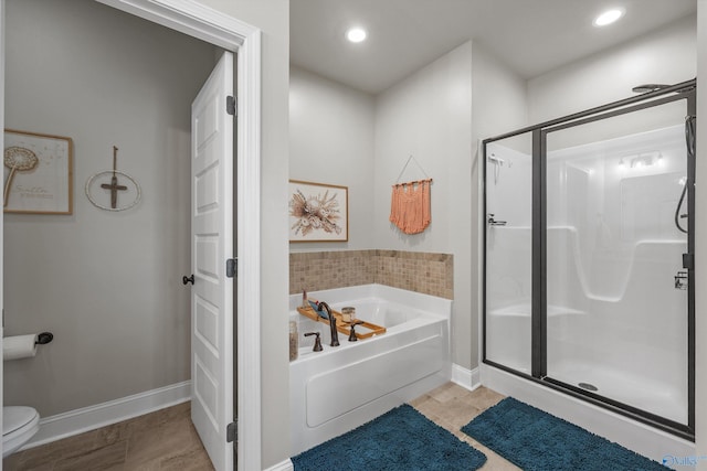 bathroom with a garden tub, toilet, a stall shower, and baseboards