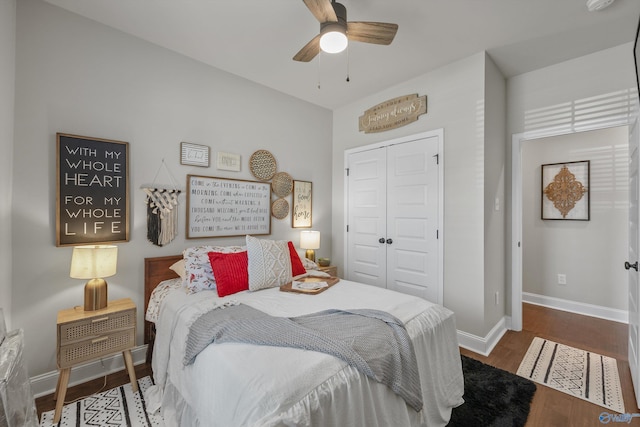 bedroom with a closet, ceiling fan, wood finished floors, and baseboards
