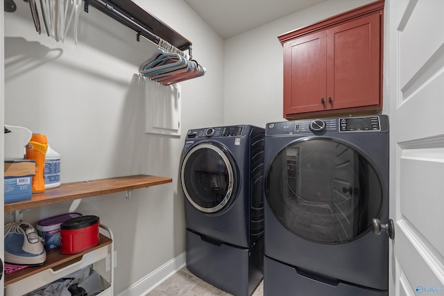washroom featuring separate washer and dryer, cabinet space, and baseboards