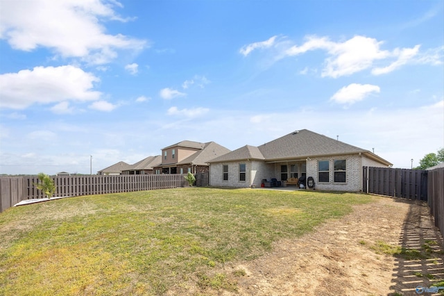 rear view of property with a lawn, brick siding, and a fenced backyard