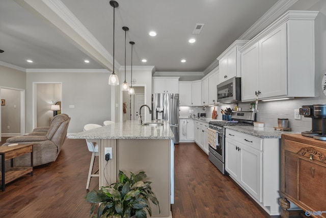 kitchen with white cabinets, a sink, stainless steel appliances, a kitchen bar, and backsplash