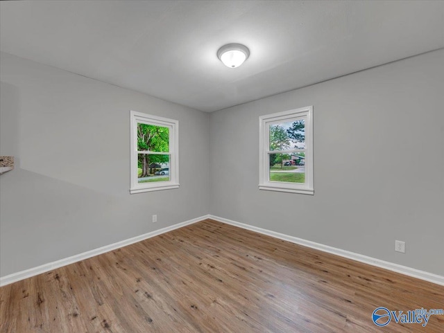 empty room with baseboards, wood finished floors, and a wealth of natural light