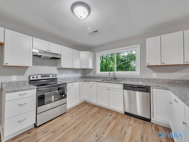 kitchen featuring visible vents, a sink, white cabinets, under cabinet range hood, and stainless steel appliances