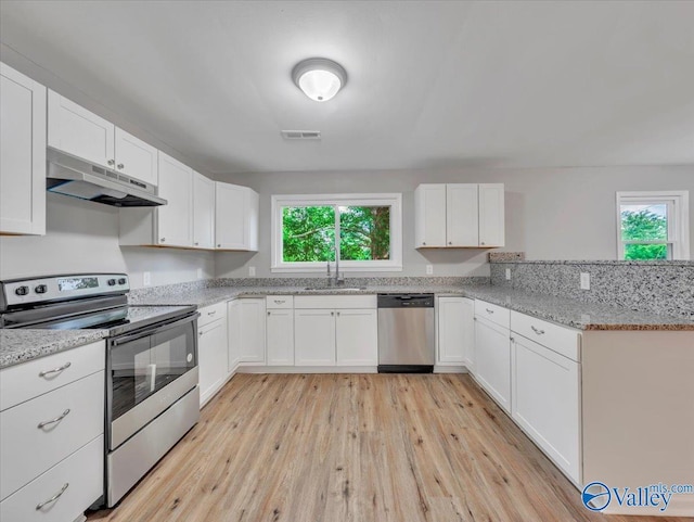 kitchen featuring a sink, stainless steel appliances, light wood-type flooring, under cabinet range hood, and visible vents