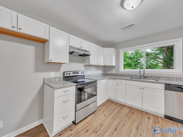 kitchen featuring visible vents, appliances with stainless steel finishes, light wood-type flooring, a sink, and under cabinet range hood