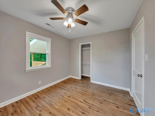 unfurnished bedroom with a ceiling fan, baseboards, wood finished floors, visible vents, and a closet