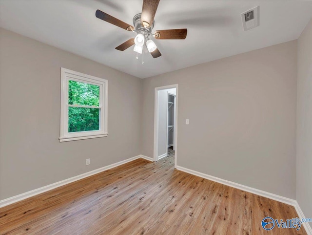 empty room featuring baseboards, a ceiling fan, light wood-type flooring, and visible vents