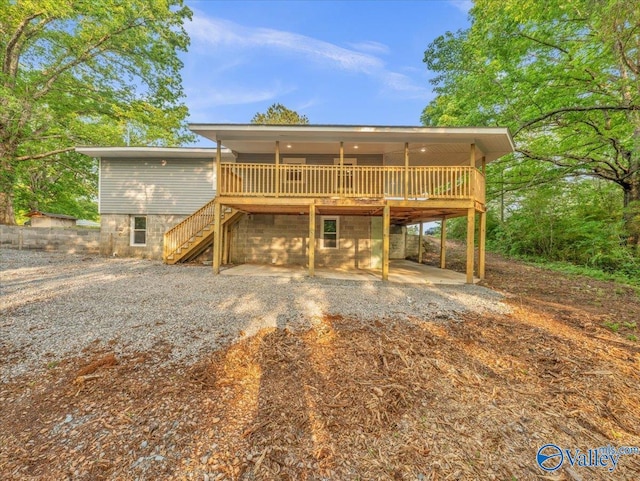 back of property with a deck, stairway, a patio area, a carport, and driveway