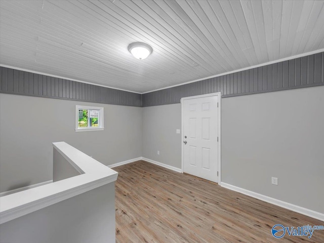 spare room featuring baseboards, wooden ceiling, and wood finished floors