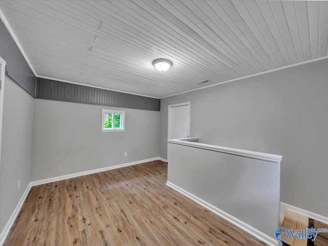 additional living space with baseboards, wood ceiling, wood finished floors, and visible vents