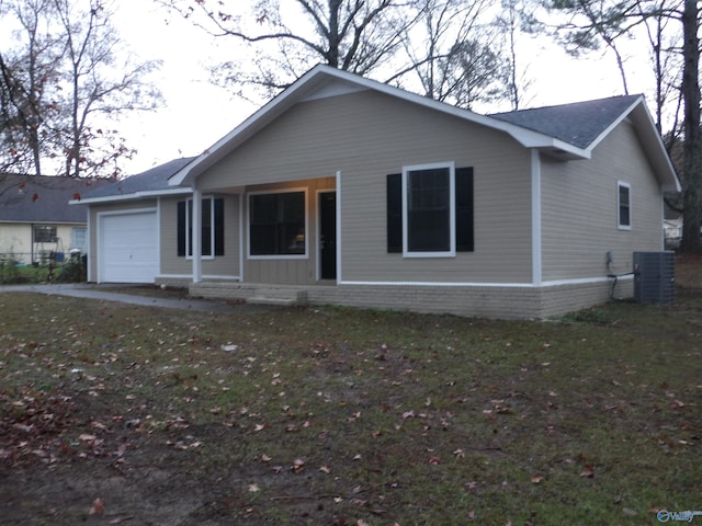 ranch-style home featuring cooling unit, a garage, and a front lawn