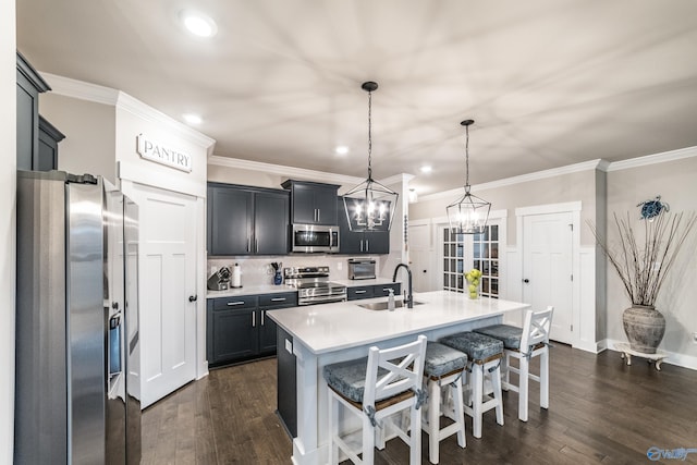 kitchen with appliances with stainless steel finishes, dark hardwood / wood-style flooring, a center island with sink, and sink