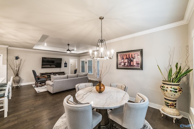 dining room with a tray ceiling, crown molding, dark hardwood / wood-style flooring, and ceiling fan with notable chandelier