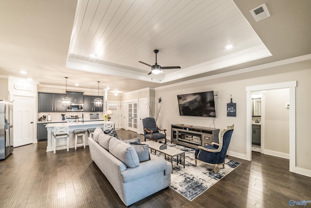 living room featuring a tray ceiling, ceiling fan, and dark wood-type flooring