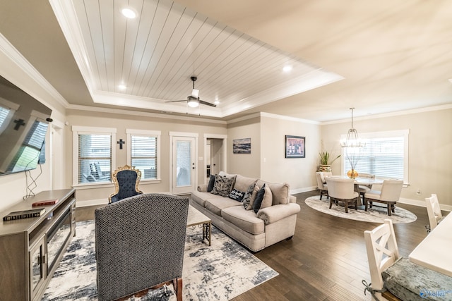 living room with a tray ceiling, a wealth of natural light, dark hardwood / wood-style flooring, and ceiling fan with notable chandelier