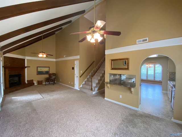 unfurnished living room featuring light carpet, a large fireplace, ceiling fan, beam ceiling, and high vaulted ceiling