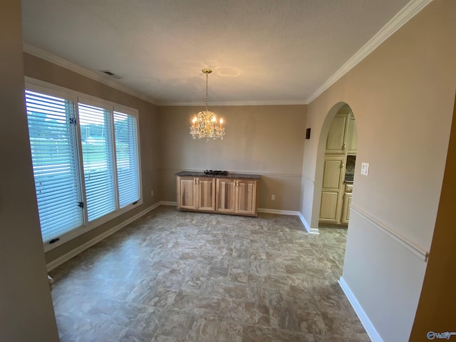 unfurnished dining area featuring a chandelier, a textured ceiling, and ornamental molding