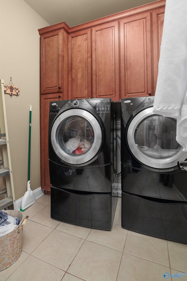 laundry room with cabinets, light tile patterned floors, and washing machine and dryer