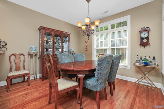 dining area featuring a healthy amount of sunlight, light hardwood / wood-style flooring, and a notable chandelier