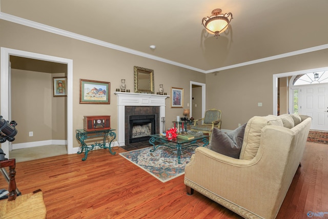 living room with ornamental molding, a tile fireplace, and hardwood / wood-style flooring