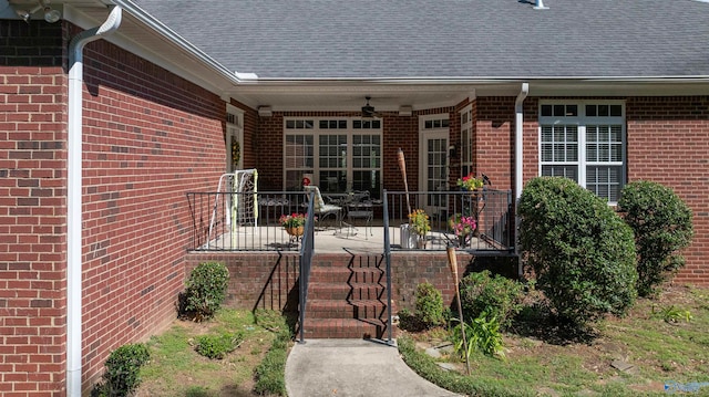 view of exterior entry with ceiling fan and a patio area